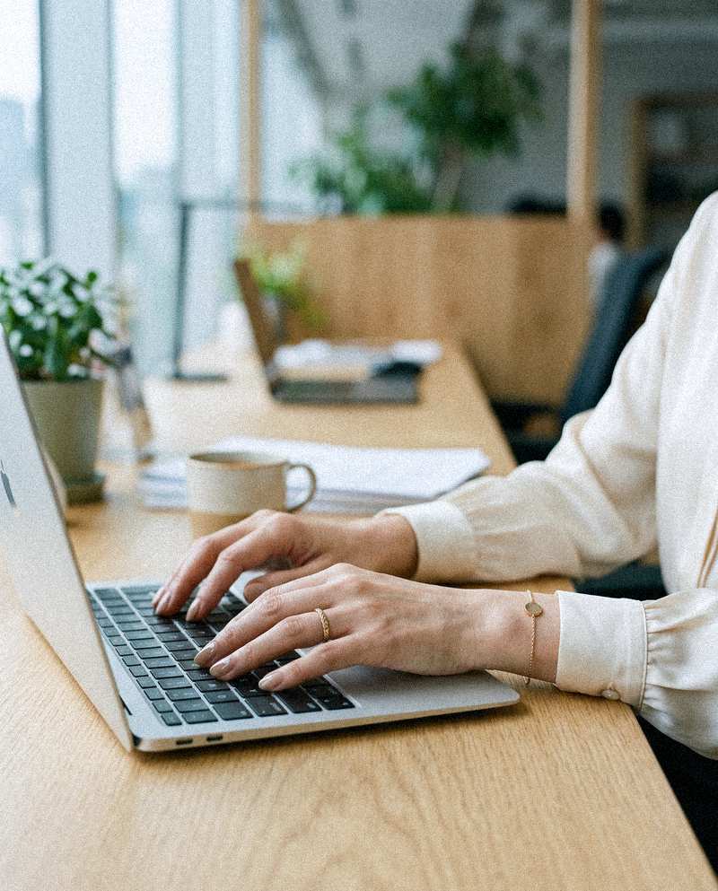 ベージュネイルの手元でキーボードを打つ様子（デモ用生成画像）